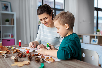 Image showing mother and son making pictures of autumn leaves