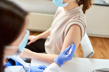 Image showing female doctor with syringe vaccinating patient