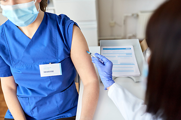 Image showing doctor with syringe vaccinating medical worker