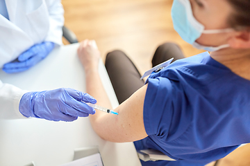 Image showing doctor with syringe vaccinating medical worker