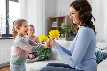 Image showing daughters giving daffodil flowers to happy mother