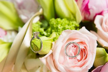 Image showing wedding rings lie on a beautiful bouquet as bridal accessories