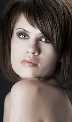 Image showing the sexy strict woman with makeup and a fashionable hairstyle poses in studio on black background