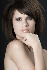 Image showing the sexy strict woman with makeup and a fashionable hairstyle poses in studio on black background