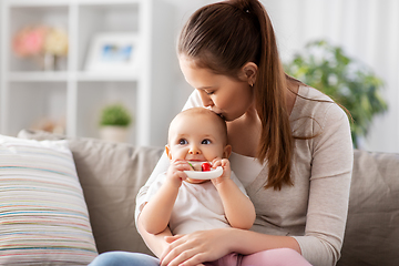 Image showing mother kissing baby with teething toy at home