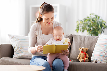 Image showing happy mother reading book to little baby at home