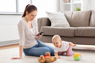 Image showing mother with smartphone and baby playing at home