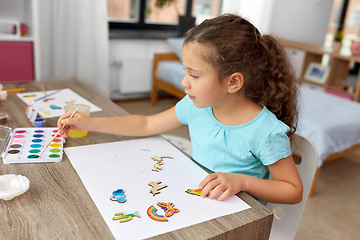 Image showing little girl painting wooden items at home