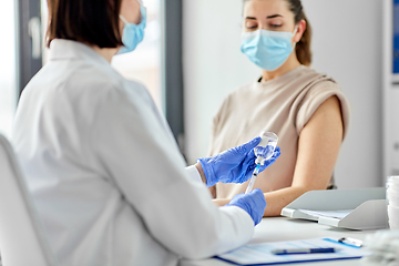 Image showing female doctor with syringe vaccinating patient