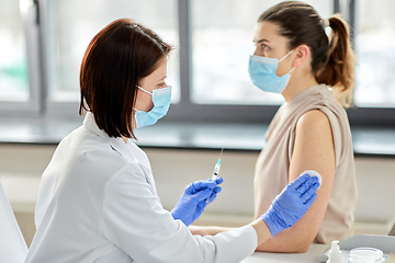 Image showing female doctor with syringe vaccinating patient