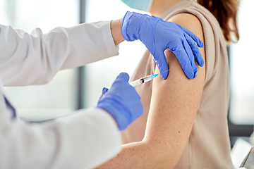 Image showing female doctor with syringe vaccinating patient