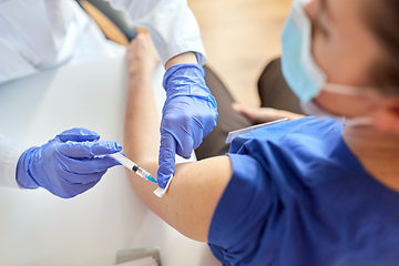 Image showing doctor with syringe vaccinating medical worker