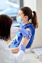 Image showing doctor with syringe vaccinating medical worker