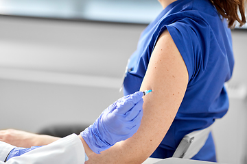 Image showing doctor with syringe vaccinating medical worker