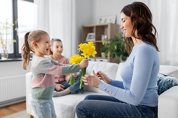 Image showing daughters giving daffodil flowers to happy mother