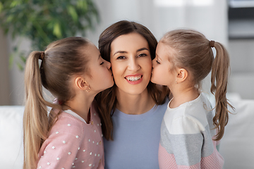 Image showing happy mother and two daughters kissing her at home