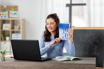 Image showing math teacher with book having online class at home