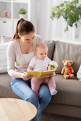 Image showing happy mother reading book to little baby at home