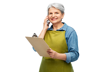 Image showing old female gardener with clipboard calls on phone