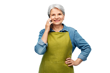 Image showing senior woman in garden apron calling on smartphone