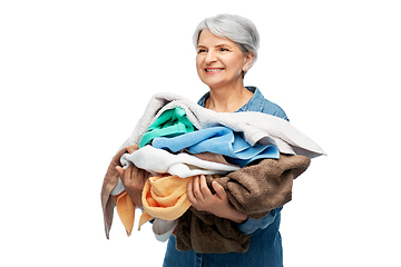 Image showing smiling senior woman with heap of bath towels