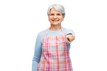 Image showing smiling senior woman in apron pointing to camera