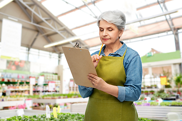 Image showing senior woman with clipboard at garden store