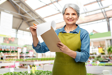 Image showing smiling old woman with clipboard at garden store
