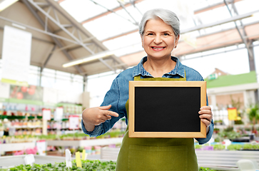 Image showing happy senior woman with chalkboard at garden store