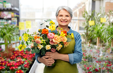 Image showing smiling senior woman with flowers at garden store