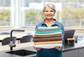 Image showing happy senior woman with clean bath towels at home