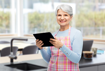 Image showing happy senior woman in apron with tablet pc at home