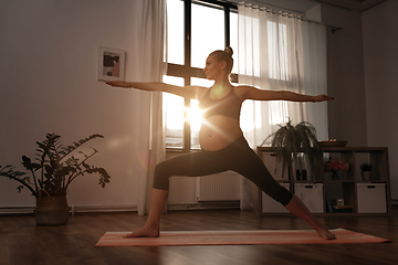 Image showing pregnant woman doing yoga at home over sunshine