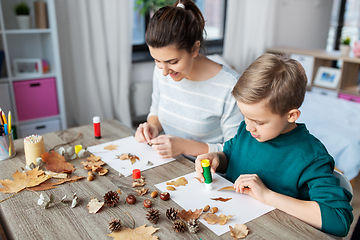 Image showing mother and son making pictures of autumn leaves