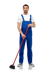 Image showing male cleaner in overall cleaning floor with broom