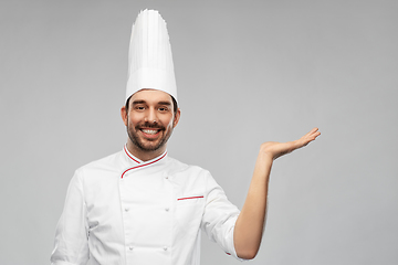 Image showing happy smiling male chef holding something on hand