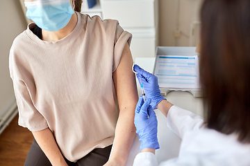 Image showing female doctor with syringe vaccinating patient