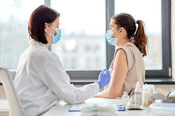 Image showing female doctor with syringe vaccinating patient