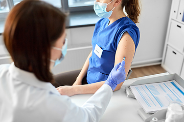 Image showing doctor with syringe vaccinating medical worker