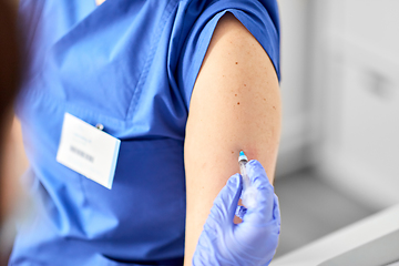 Image showing doctor with syringe vaccinating medical worker