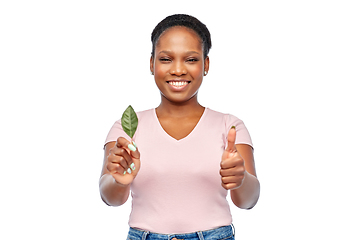Image showing smiling african american woman holding green leaf