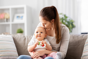 Image showing mother kissing baby with teething toy at home