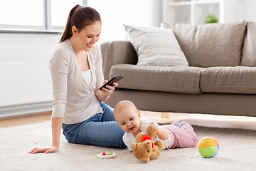 Image showing mother with smartphone and baby playing at home