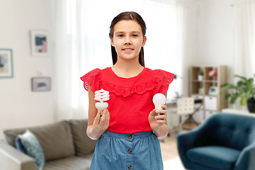 Image showing smiling girl comparing different light bulbs