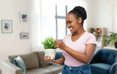 Image showing happy smiling african woman holding flower in pot