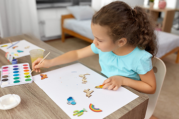 Image showing little girl painting wooden items at home