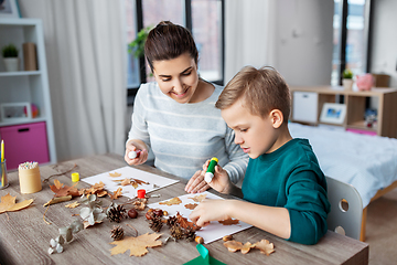 Image showing mother and son making pictures of autumn leaves