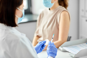 Image showing female doctor with syringe vaccinating patient