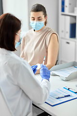 Image showing female doctor with syringe vaccinating patient