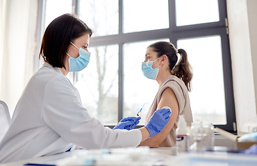 Image showing female doctor with syringe vaccinating patient